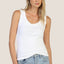 Woman wearing a white tank top and blue jeans against a plain background