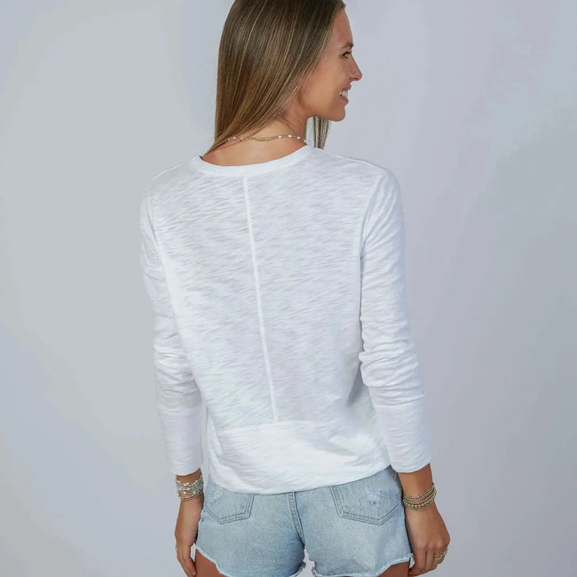 Woman wearing a white long-sleeve top and denim shorts against a plain background Secondary image