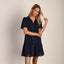 Woman wearing navy Malia Dress with short sleeves, button front, and eyelet lace trim hem
