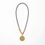 Necklace with a gold pendant on a gray cord against a white background