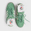 A pair of mint green low-top sneakers with white socks peeking out from the toes, photographed from above on a light gray background.