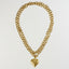 A gold-toned double-strand chain necklace with a polished heart-shaped pendant, displayed against a solid white background.