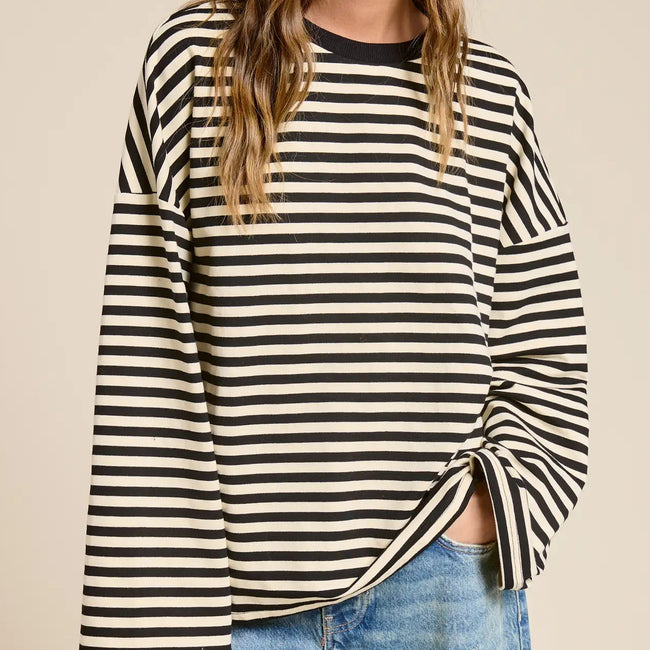 Woman wearing black and cream striped oversized long sleeve terry top with ruched side detail, paired with light blue jeans Main image