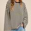 Woman wearing black and cream striped oversized long sleeve terry top with ruched side detail, paired with light blue jeans