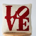 Knitted pillow with 'LOVE' in red on a white background