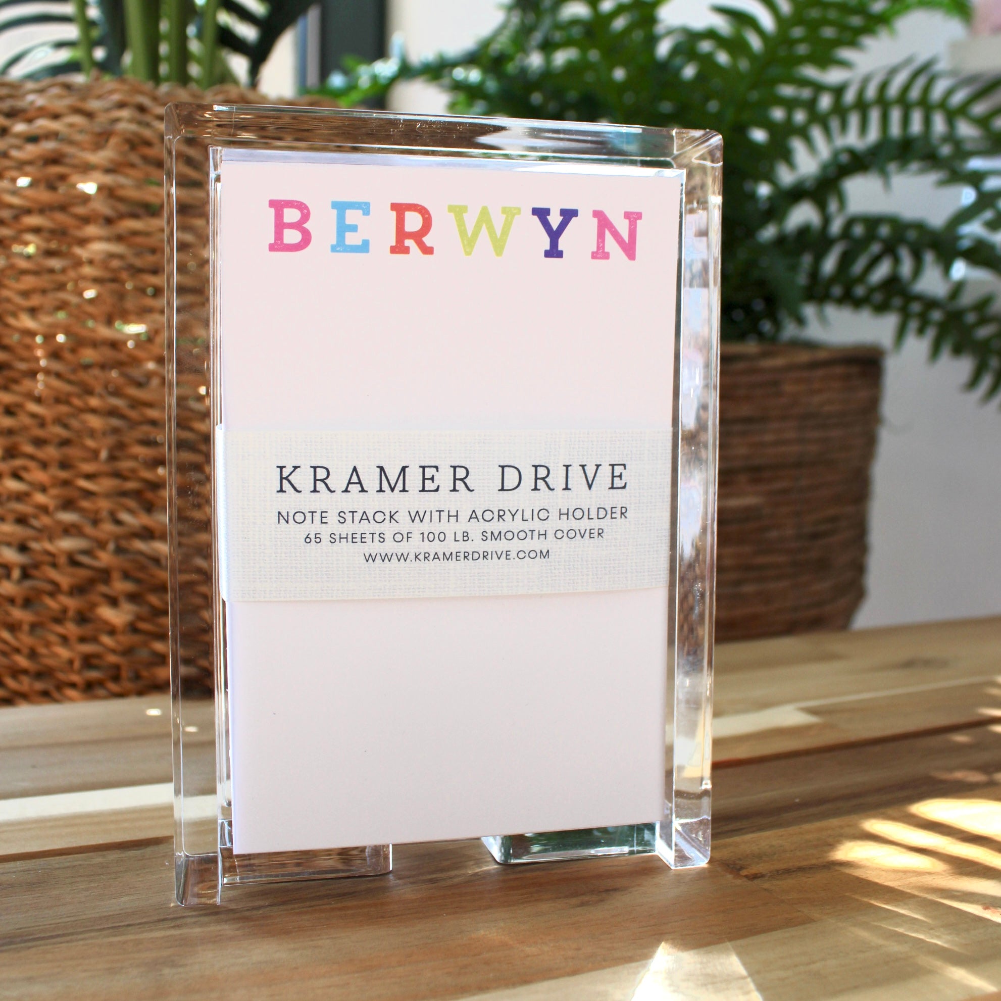 Colorful Berwyn notepad with acrylic holder containing 65 sheets of smooth cover paper, displayed on wooden surface with pot…