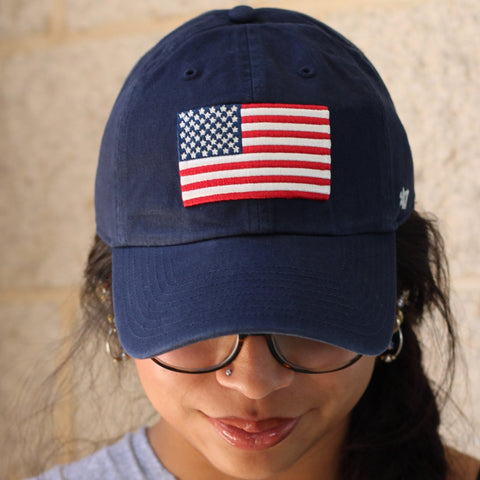 Person wearing a navy blue hat with an american flag on it