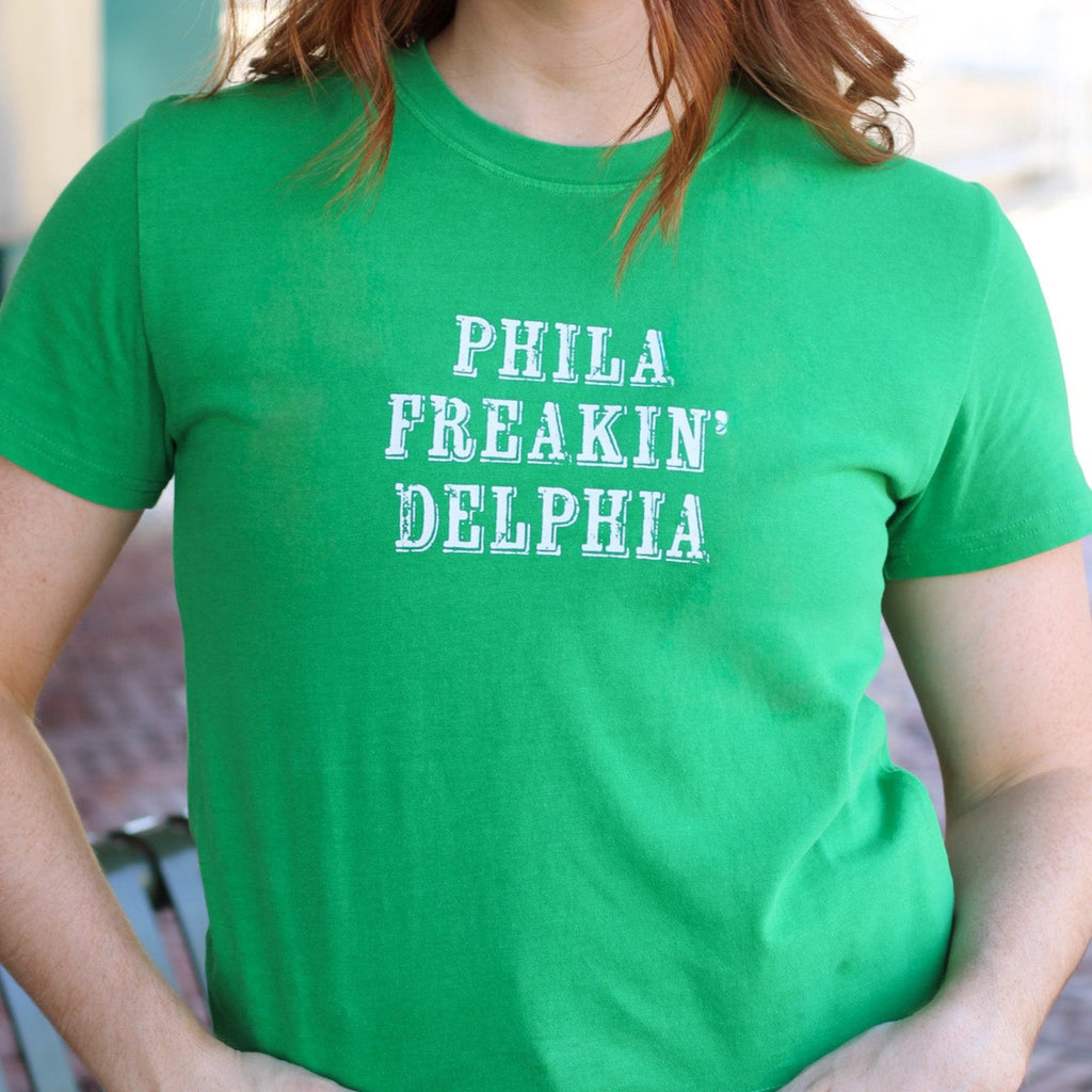 Woman wearing bright green cotton t-shirt with white text reading 'PHILA FREAKIN' DELPHIA'
