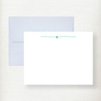 White flat note cards with teal script initial and matching light blue envelopes displayed on cream background