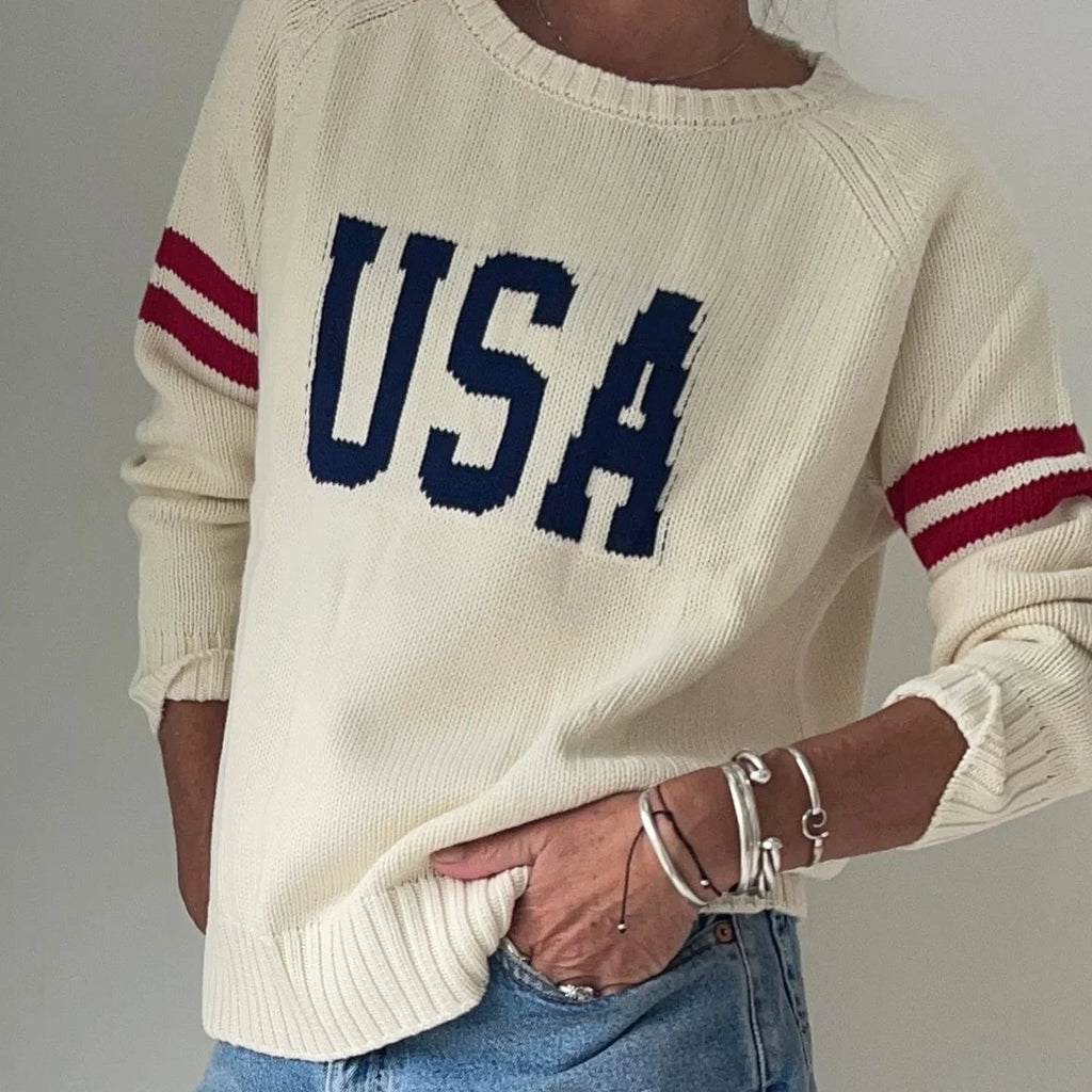 Cream knit sweater with navy USA lettering and burgundy striped sleeves, styled with denim and silver bracelets