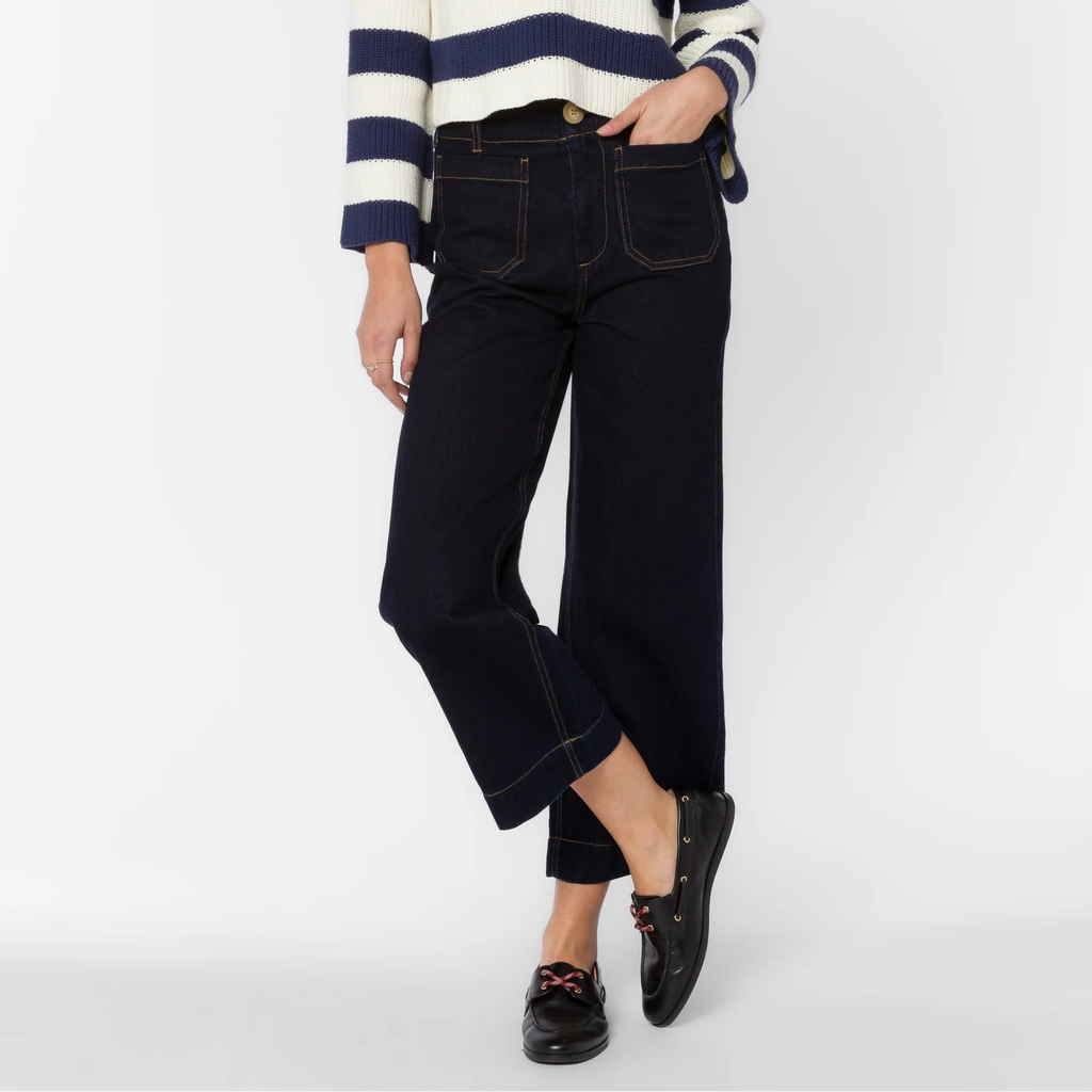 Woman wearing navy Alyx high-rise cropped wide-leg jeans with contrast stitching, paired with navy and cream striped sweater…