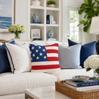 Living room with a white sofa adorned with decorative pillows, including an American flag design, and a coffee table with books and a lamp.
