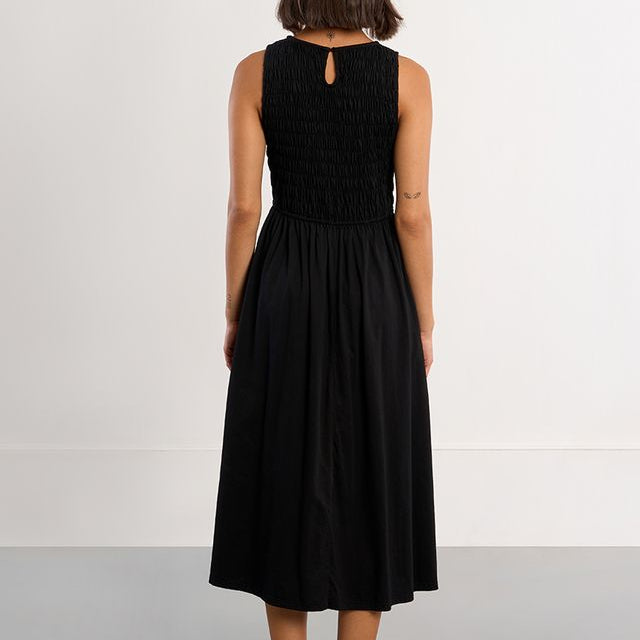 Woman wearing a black sleeveless dress against a white background
