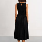 Woman wearing a black sleeveless dress against a white background