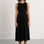 Woman wearing a black sleeveless dress with a plain background
