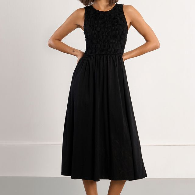 Woman wearing a black sleeveless dress with a plain background