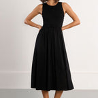 Woman wearing a black sleeveless dress with a plain background
