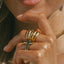 Blair Ring featuring stacked gold bands with black cross pendant, worn on hand with natural nails and beaded bracelet