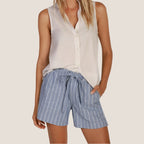 Woman wearing white sleeveless button-up blouse with blue pinstriped shorts and drawstring waist