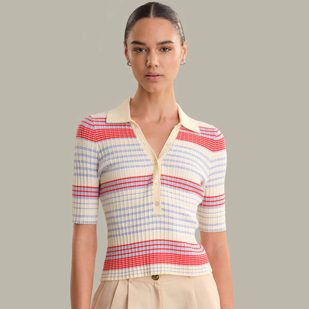 Woman wearing a cream, red and blue striped ribbed polo shirt with half sleeves and collar Main image