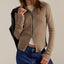 Woman wearing beige cable-knit zip-up cardigan over white tee with dark jeans, holding black leather jacket