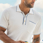 Man wearing a white textured polo shirt with blue trim against a blurred outdoor background
