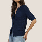 Woman wearing navy cable knit cardigan with short sleeves and button front over light blue jeans