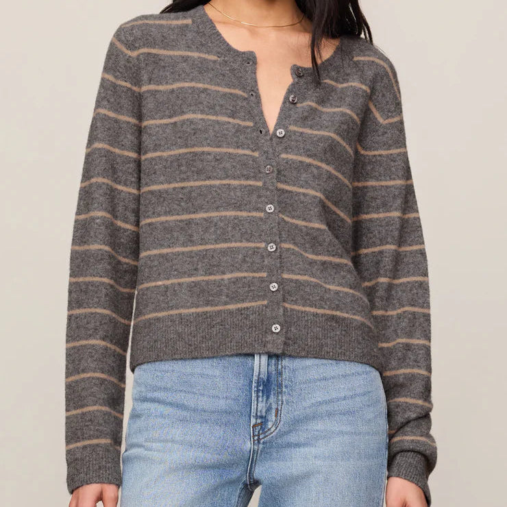 Woman wearing a striped sweater and jeans against a plain background
