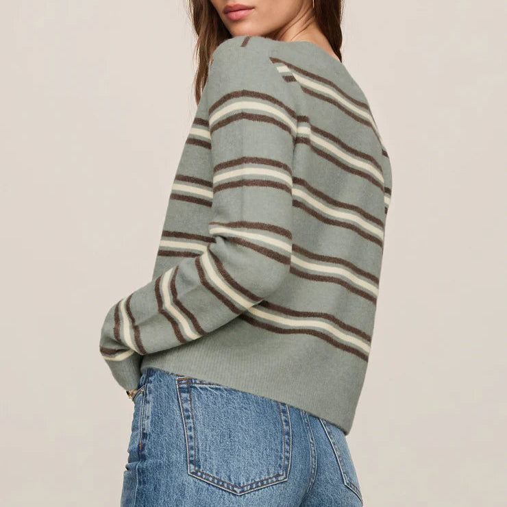 Woman wearing a striped sweater and jeans against a plain background