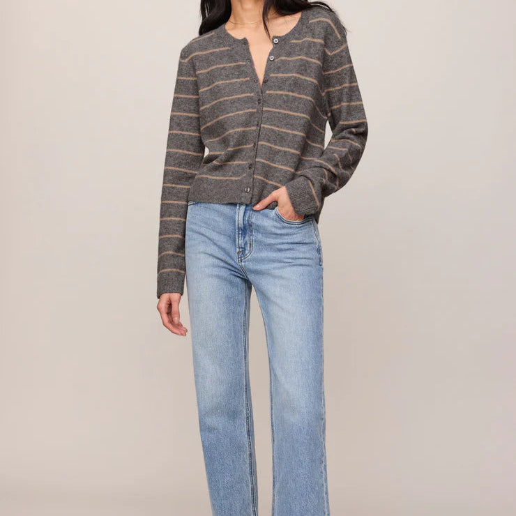 Woman wearing a striped sweater and light blue jeans on a plain background