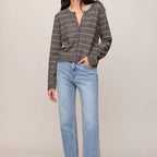 Woman wearing a striped sweater and light blue jeans on a plain background