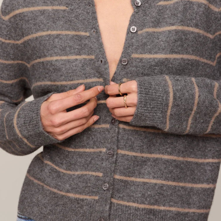 Woman wearing a gray striped cardigan against a neutral background