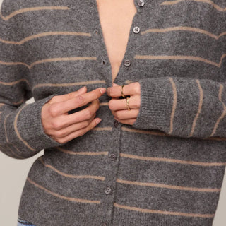 Woman wearing a gray striped cardigan against a neutral background