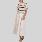 Woman wearing cream ribbed sweater with black horizontal stripes and tiered cream midi skirt with sandals