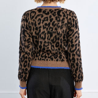 A model viewed from the back wearing a brown and black leopard-print knit sweater with blue trim, paired with black trousers, against a plain white studio background.