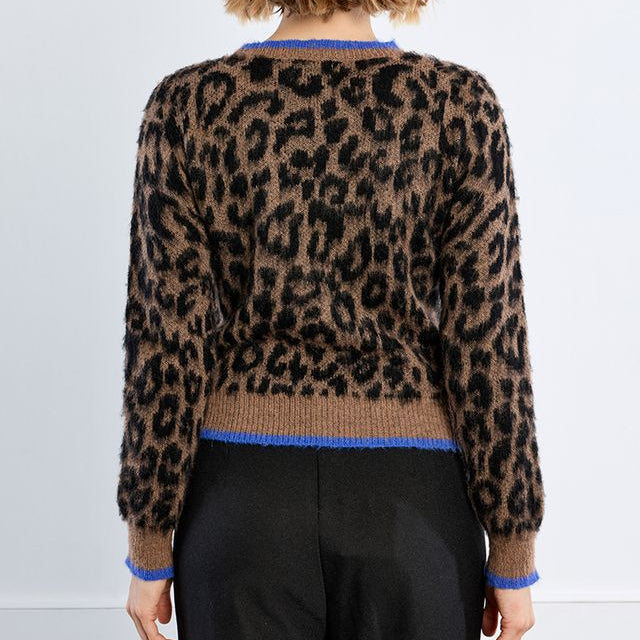 A model viewed from the back wearing a brown and black leopard-print knit sweater with blue trim, paired with black trousers, against a plain white studio background.