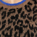 Close-up of a knit sweater featuring a brown and black leopard print pattern with a bright blue ribbed crew neck.