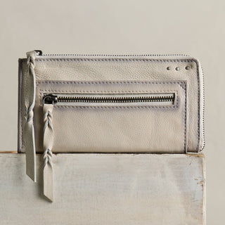 Cream leather wallet with wristlet strap, front zipper pocket, and decorative stud details