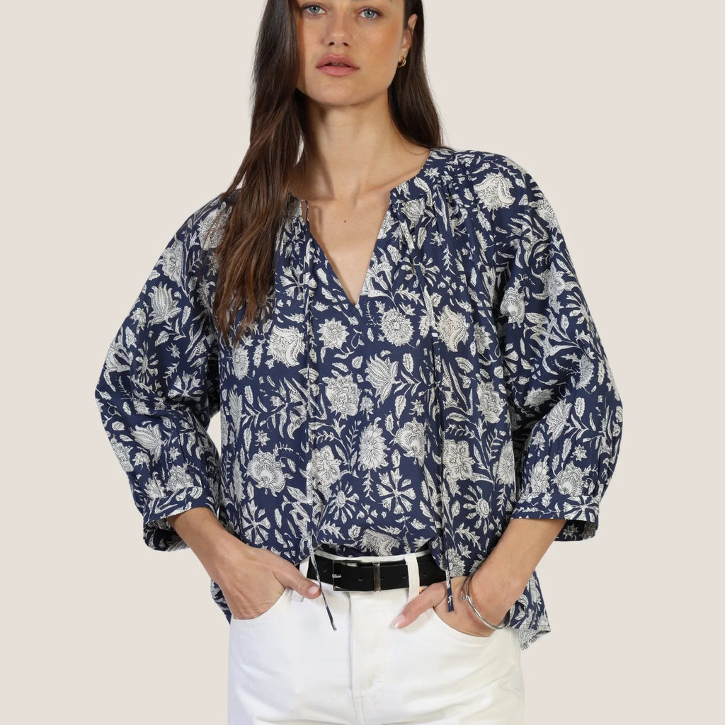 Woman wearing Emma Top in navy with cream floral print, paired with white pants and black belt