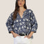 Woman wearing Emma Top in navy with cream floral print, paired with white pants and black belt