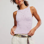 Woman wearing lavender sleeveless tank with delicate eyelet pattern and cream trousers with patterned belt