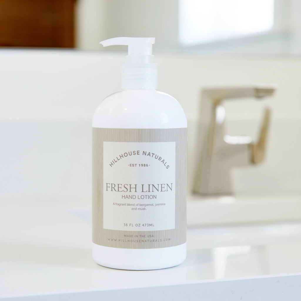Hillhouse Naturals Fresh Linen hand lotion pump bottle with beige label, 16 fl oz, displayed in a bright bathroom setting