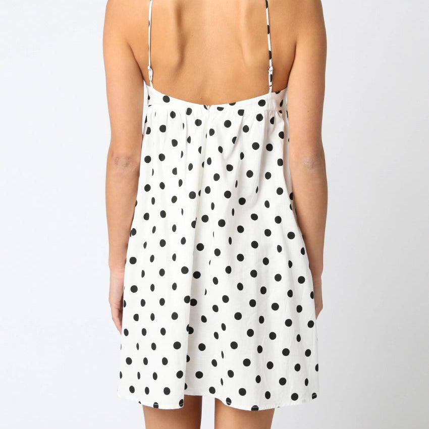 Woman wearing a polka dot dress with thin straps on a white background