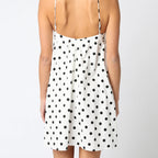 Woman wearing a polka dot dress with thin straps on a white background