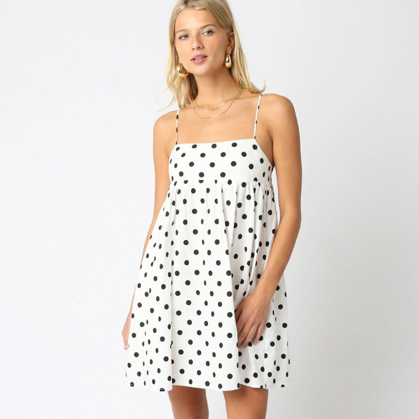 Woman wearing a white dress with black polka dots on a white background