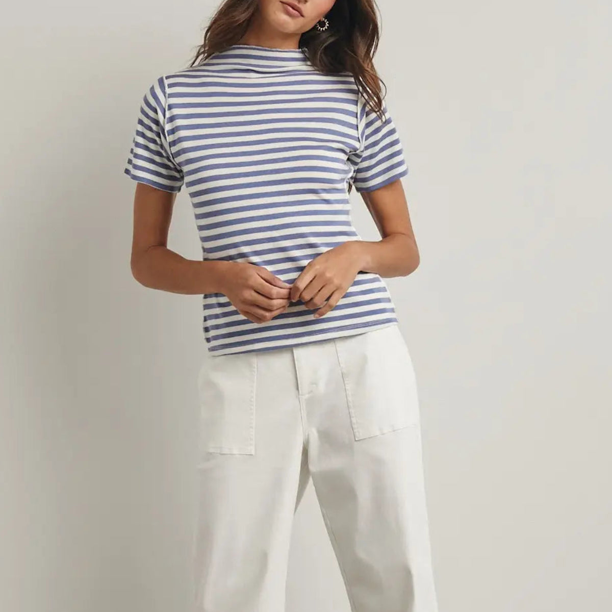 Woman wearing navy and white striped mock neck short-sleeve tee with cream white pants and silver star earrings Main image