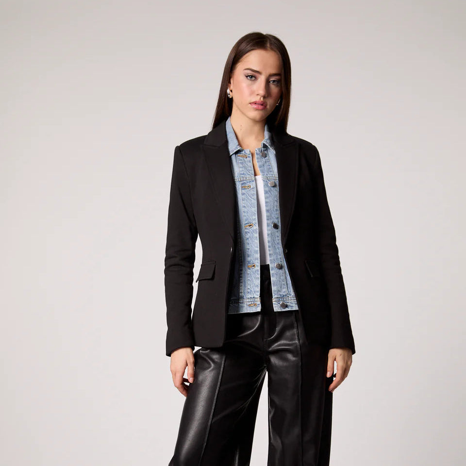 Woman wearing black Helen Blazer over light blue denim shirt and black leather pants, styled for modern professional look Main image
