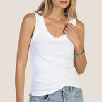 Woman wearing a white tank top with lace details on a beige background