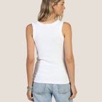 Woman wearing a white sleeveless top and light blue denim shorts on a beige background