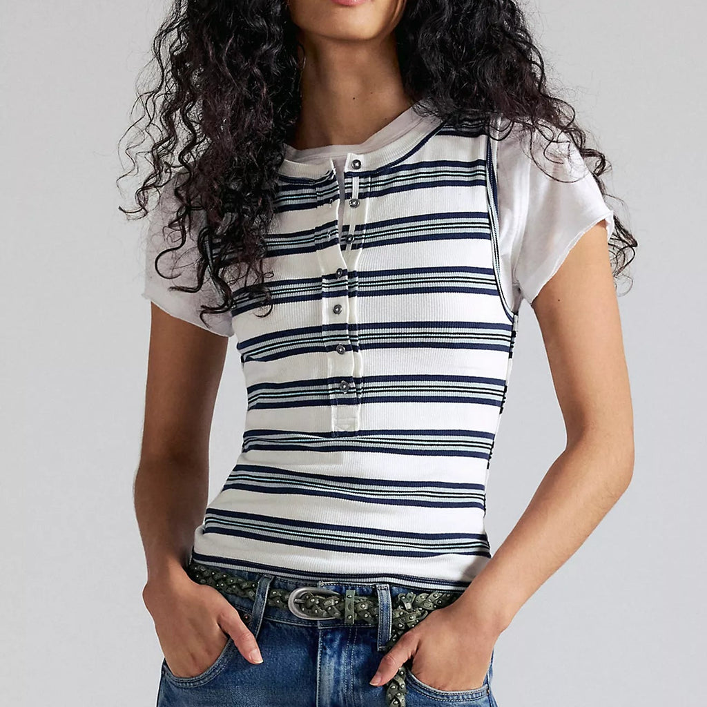 Woman wearing a striped shirt and jeans against a plain background